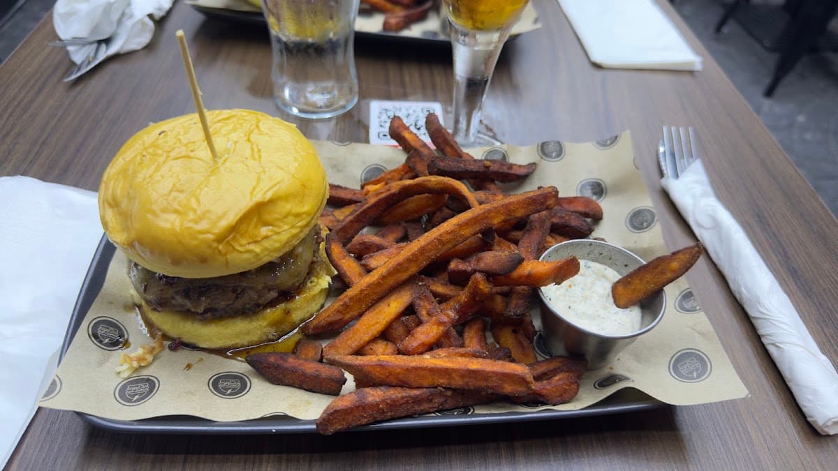 Mesa servida con hamburguesas y patatas en Burguitos